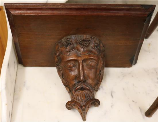 A Victorian oak clock bracket supported by a laurel wreathed mask, W.41cm